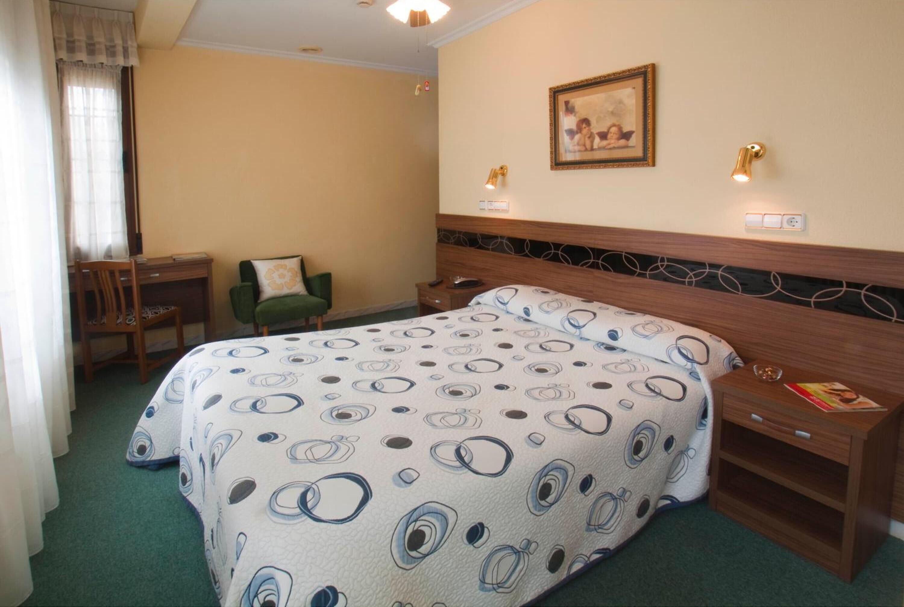 Una habitación de hotel con cama, escritorio, silla y mesita de noche.