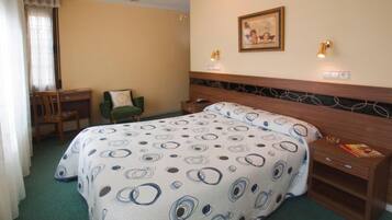 Una habitación de hotel con cama, escritorio, silla y mesita de noche.
