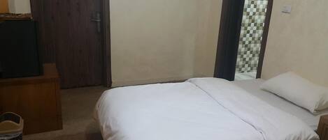 A bedroom with a bed, a wooden dresser, and a door.