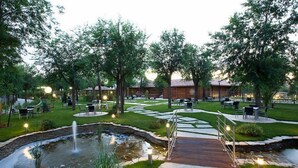 A landscaped outdoor area with a pond, seating areas, and a wooden deck. - Complejo La Cigüeña (Arganda del Rey)