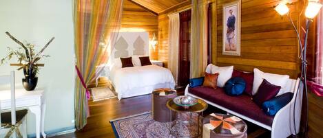 A cozy room with a bed, a sofa, a coffee table, and a chair.