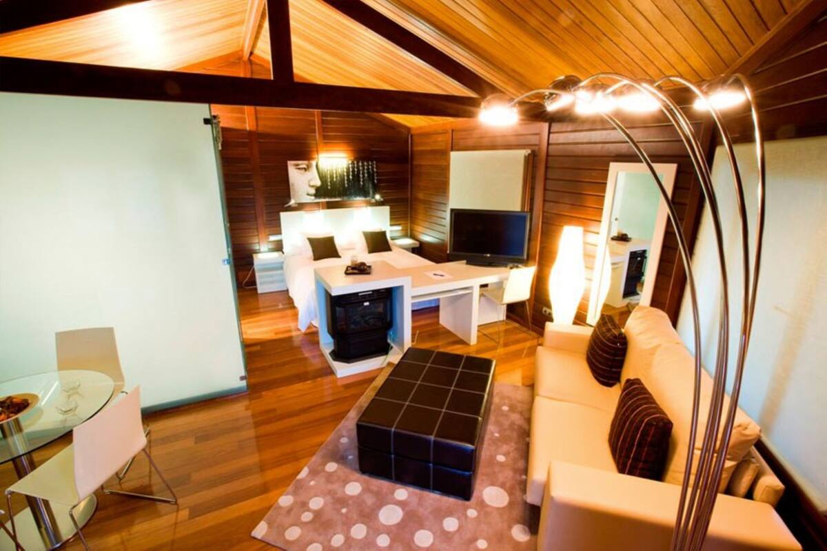A modern interior with a wooden ceiling, a sofa, a coffee table, a TV, and a dining area.