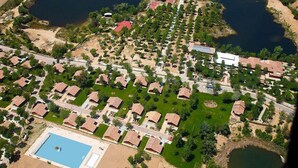 An aerial view of a resort with multiple bungalow-style accommodations, a central pool, and surrounding natural landscapes. - Complejo La Cigüeña (Arganda del Rey)