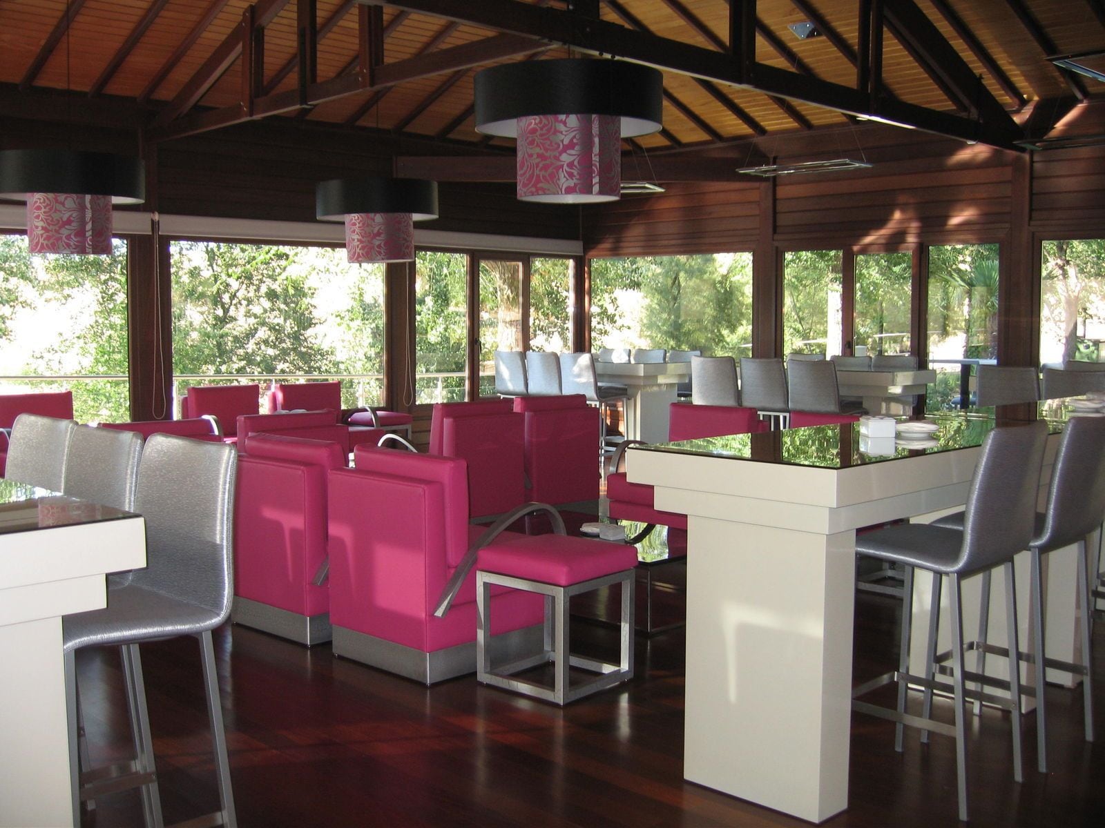 A restaurant with red and gray seating, large windows, and hanging lamps.