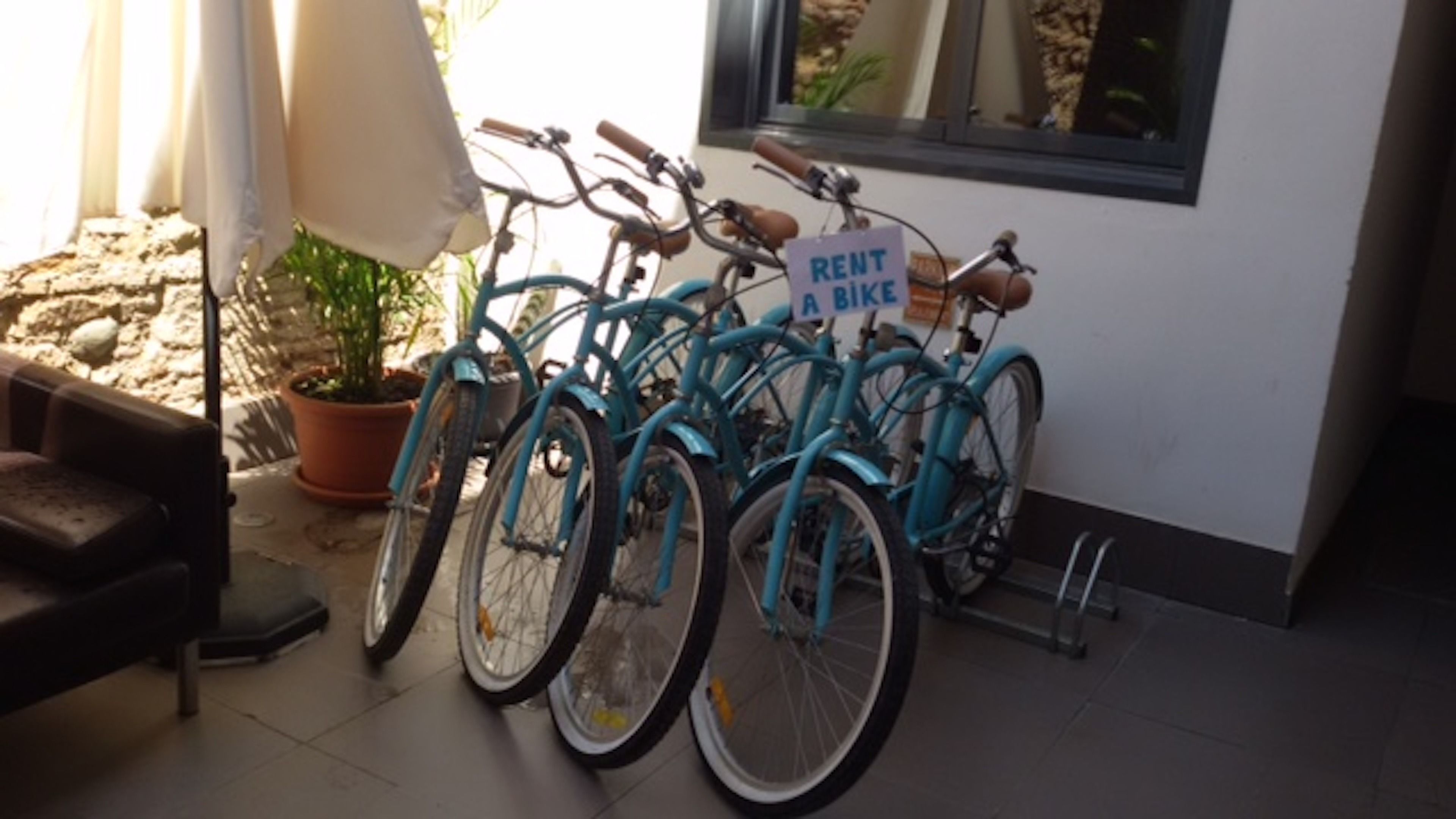 Varias bicicletas azules estacionadas en el interior, con un cartel que dice 'RENT A BIKE'.