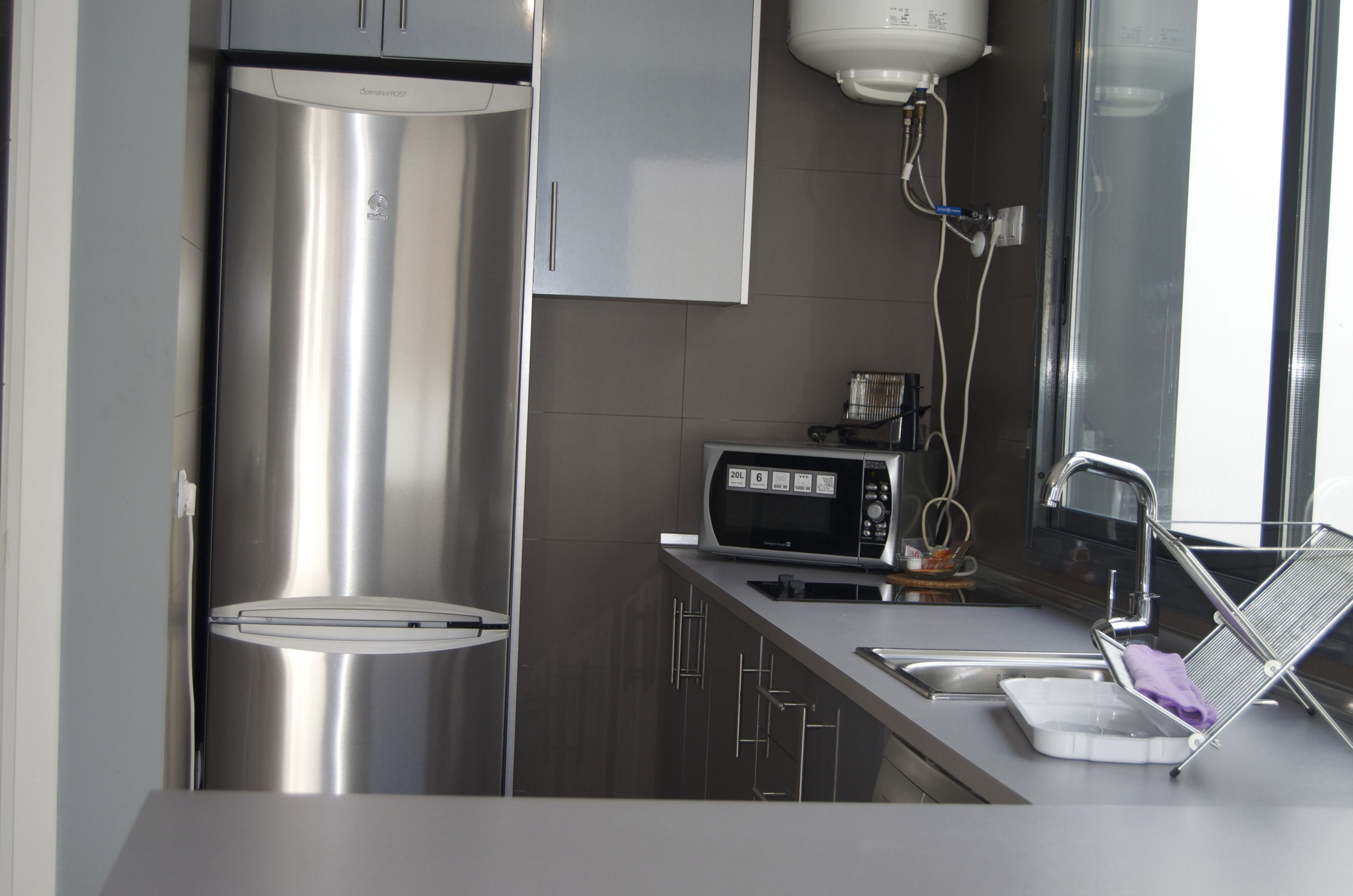 A modern kitchen with stainless steel appliances, a microwave, and a sink with a drying rack.