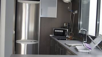 A modern kitchen with stainless steel appliances, a microwave, and a sink with a drying rack.
