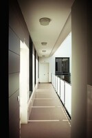 A long, narrow hallway with a tiled floor and a balcony on the right side.