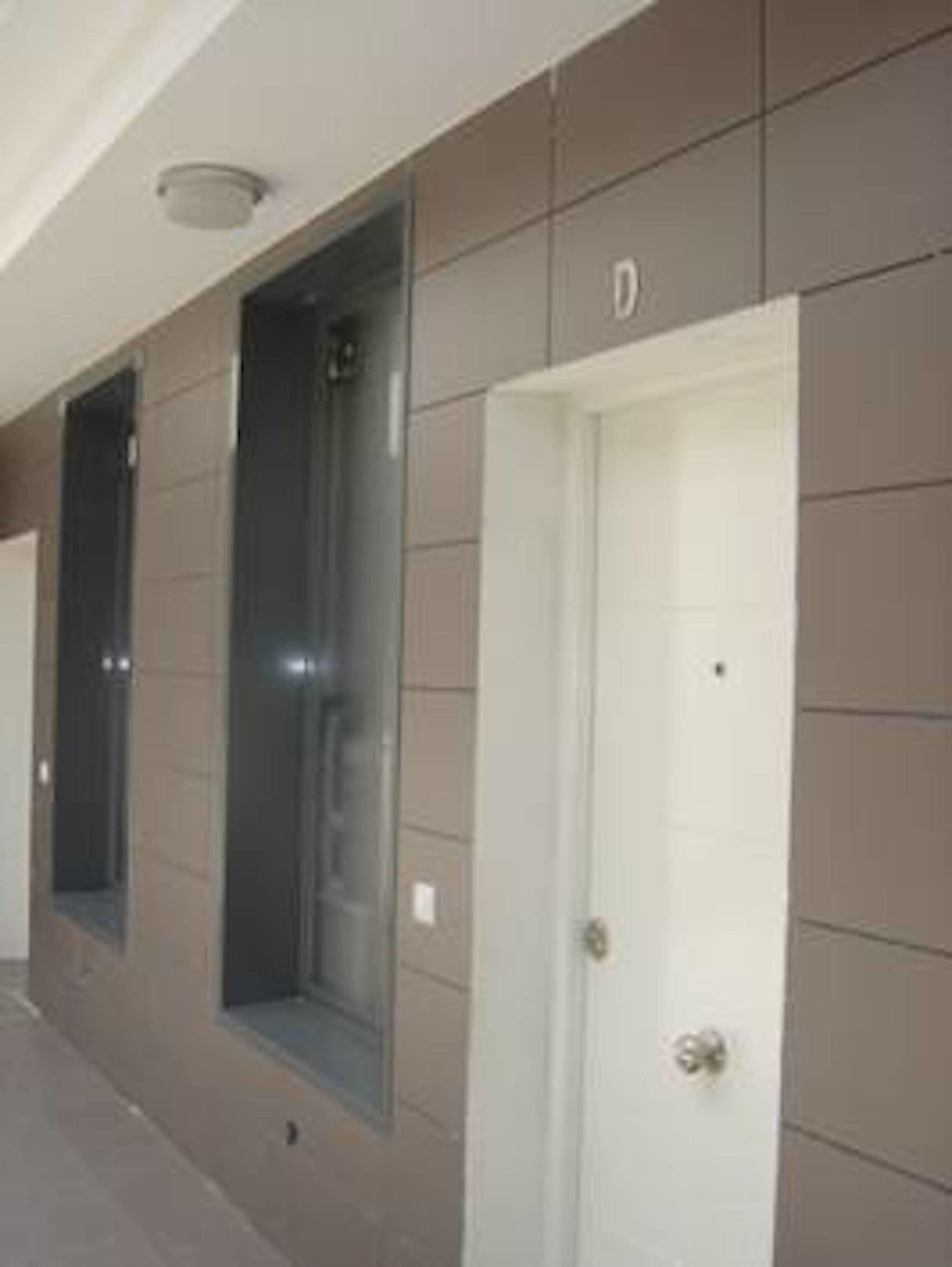 A corridor with a door labeled 'D' and a window with a view of a building.