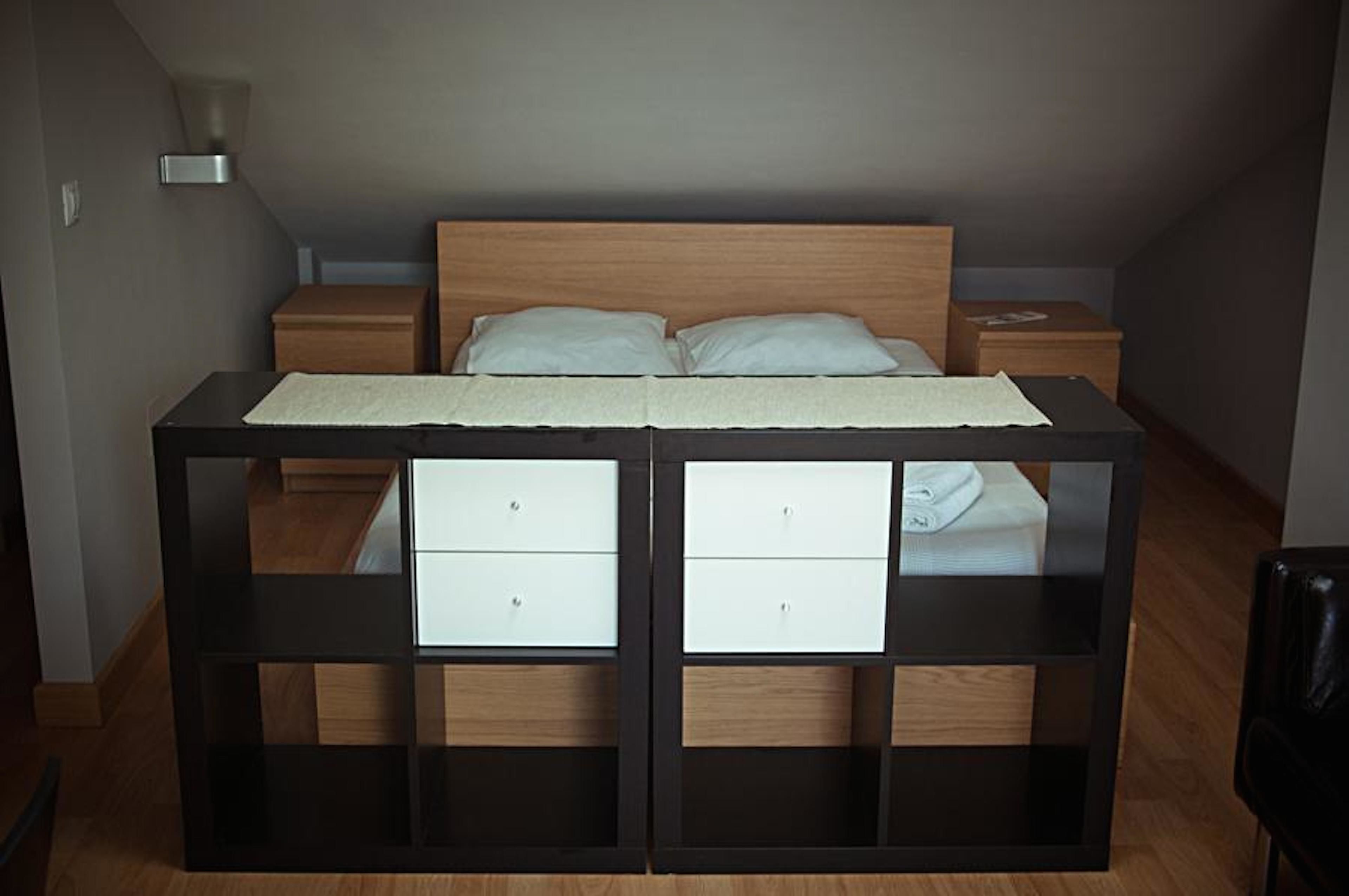 A bedroom with a bed, two nightstands, and a built-in storage unit with drawers.