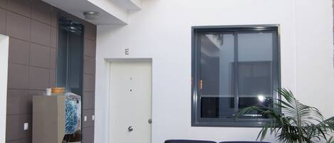 A modern lobby with a seating area, a refrigerator, and a door marked with the letter 'E'.