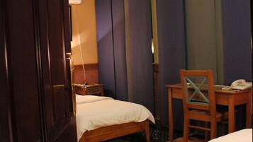 A hotel room with two beds, a desk, and a chair.