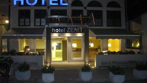 Un hôtel appelé « Hôtel Zenit », doté d’une entrée imposante, d’une enseigne lumineuse et d’une façade symétrique.
