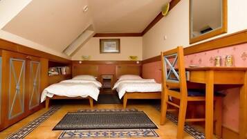 A bedroom with two beds, a desk, a chair, and a mirror.