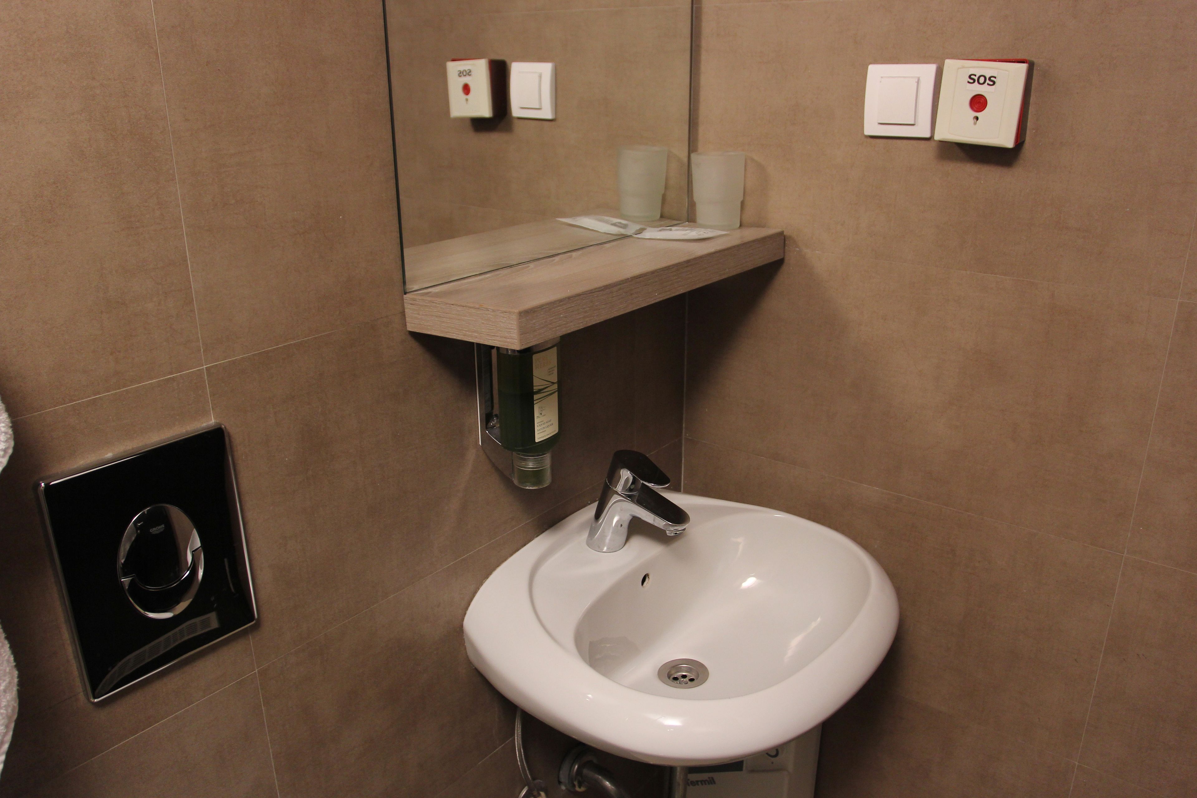 A bathroom with a white sink, a mirror, and a towel rack.