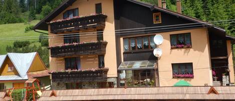 A multi-story building with balconies, a glass door entrance, and a stone facade.
