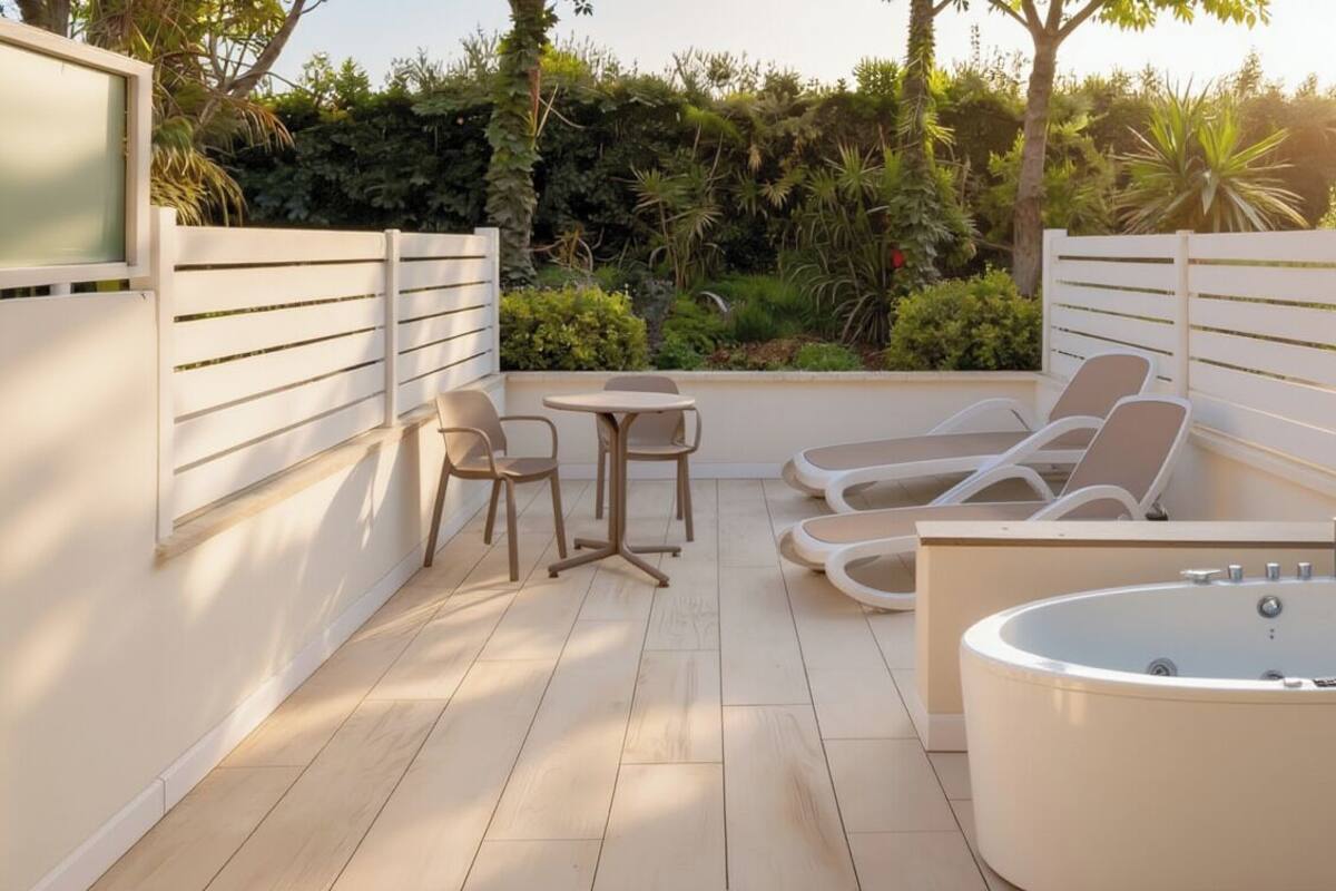 A modern outdoor spa area with a large bathtub, lounge chairs, and a small table.