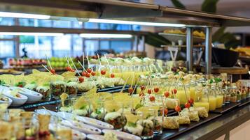 Un buffet proposant une variété de plats et de boissons, notamment des salades, des sandwichs et des fruits.