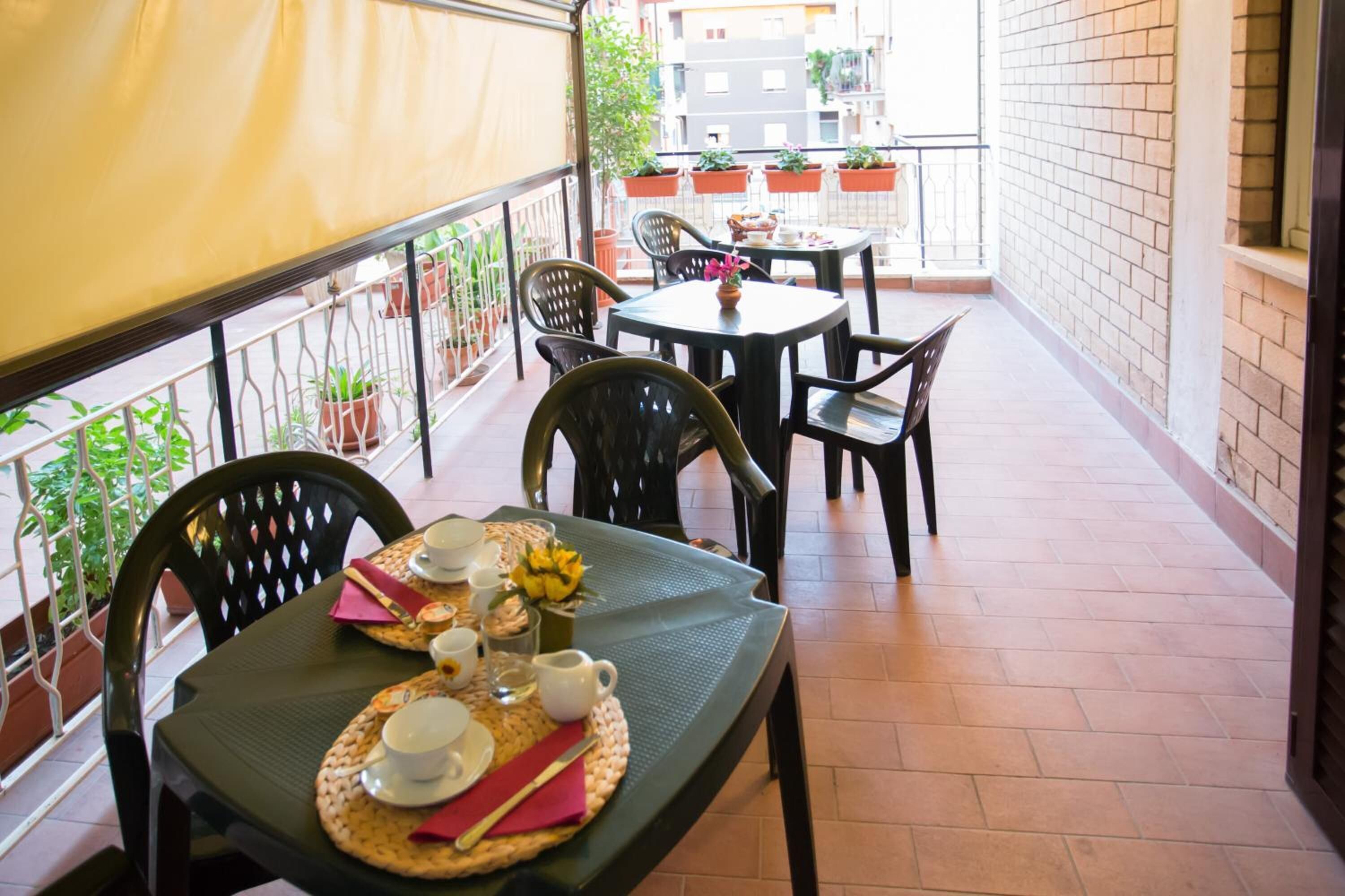 A balcony with a table set for two, chairs, and potted plants.