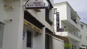 A hotel named "San Roque" with a sign above the entrance, a stone-paved street, and potted plants at the entrance. - Hotel San Roque (La Taha)