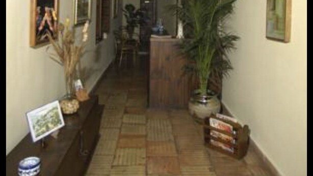 A hallway with wooden beams, framed pictures on the walls, and potted plants. - Hotel San Roque (La Taha)