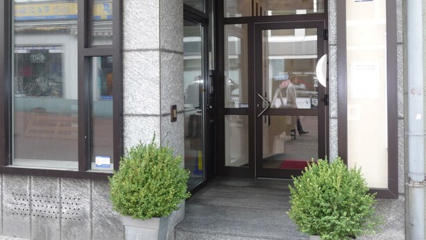 A building entrance with a glass door, a small step, and two potted plants. - Hotel Sechzehn (Leverkusen)