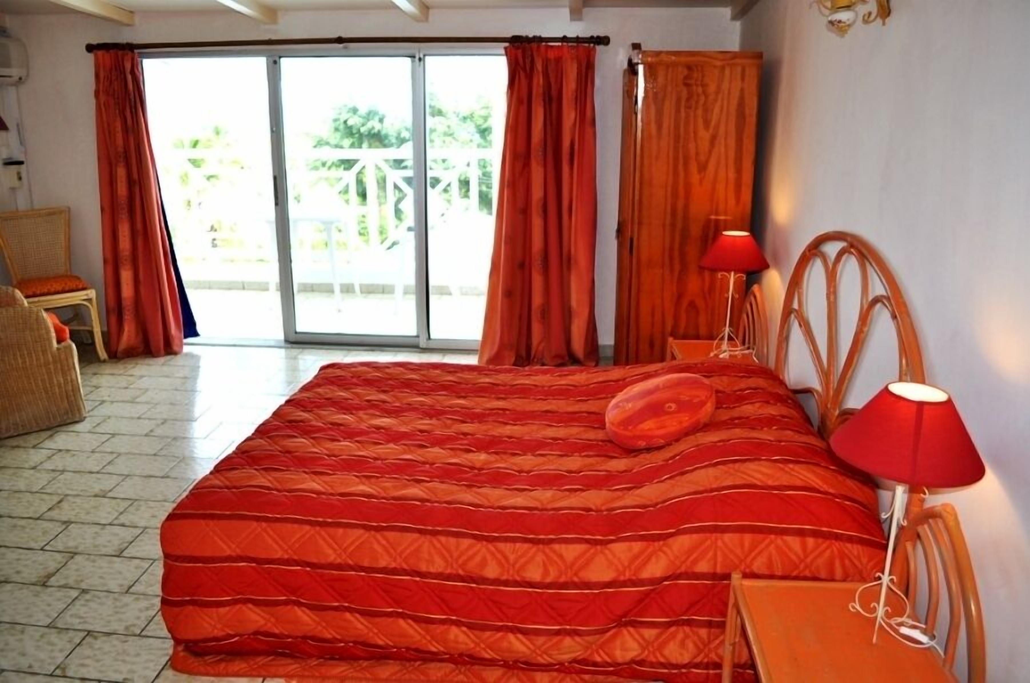 Una camera da letto con un letto grande, una testata in legno, una lampada rossa e vista tramite una porta a vetri scorrevoli.