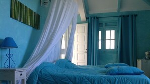 Quarto com uma cama, mesa de cabeceira, abajur e janela com cortinas.