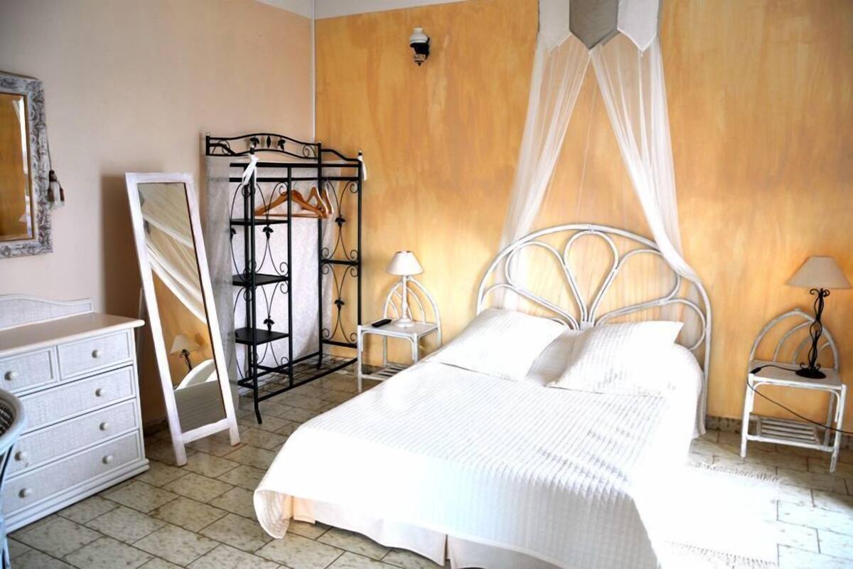 A bedroom with a bed, bedside tables, a wardrobe, and a mirror.