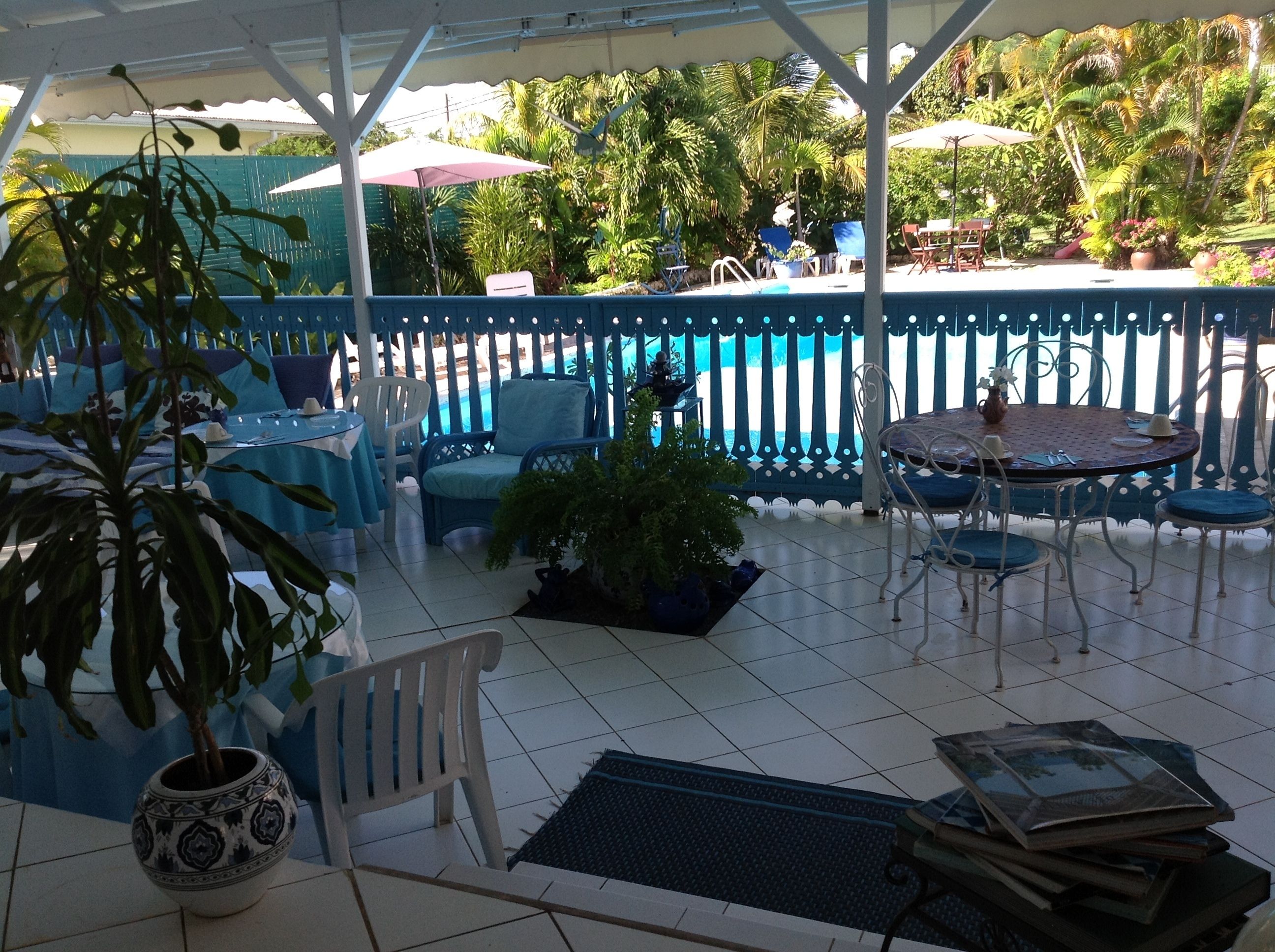 Ein überdachter Patio-Bereich mit Pool, Gartenmöbeln und Topfpflanzen.