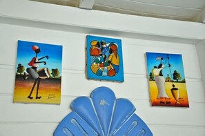 Tres cuadros en una pared, cada uno representando figuras abstractas en diferentes colores y posturas.