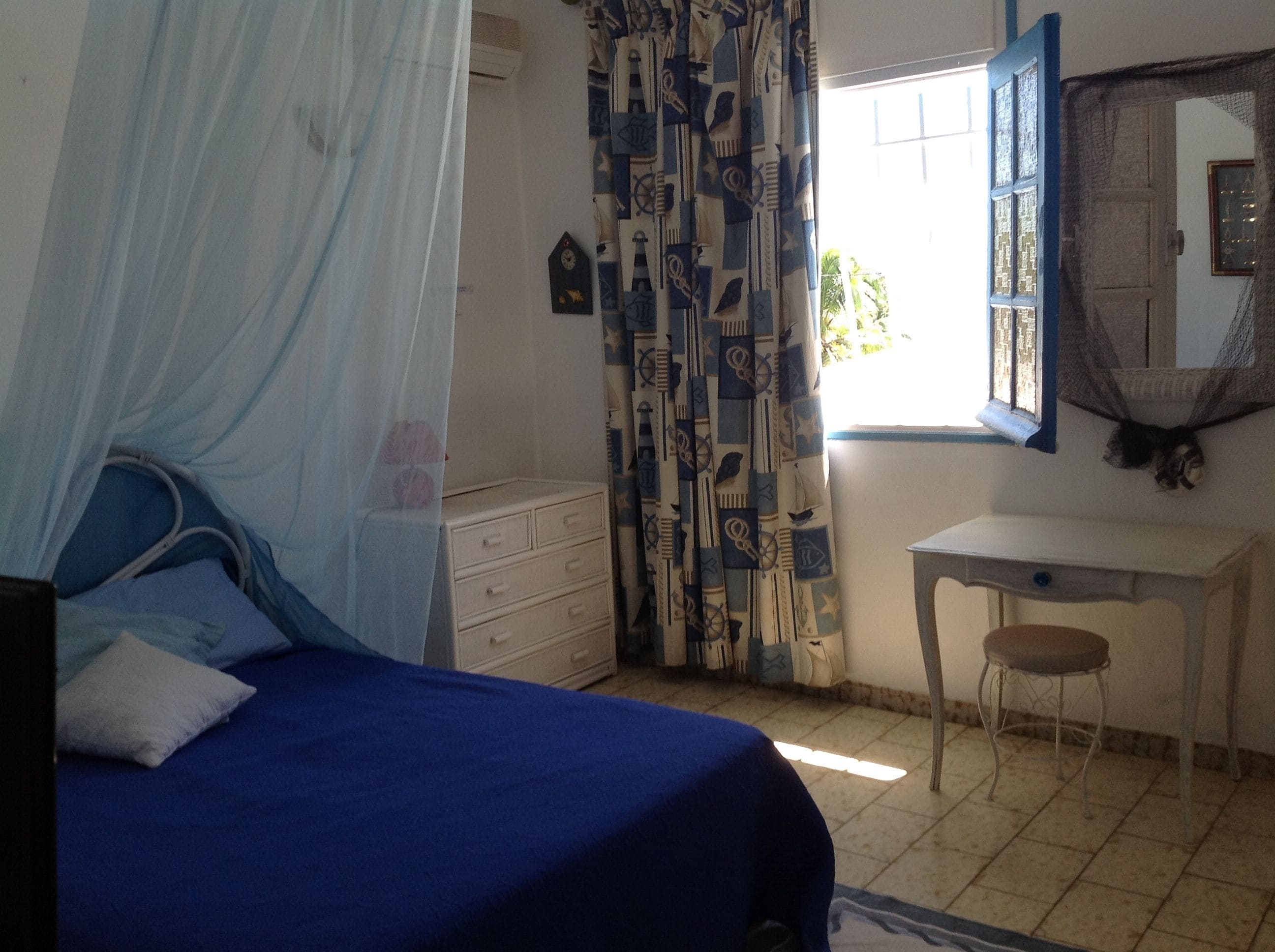 Quarto com cama, cômoda, escrivaninha e cadeira.