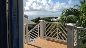 Uma varanda com vista para o oceano e palmeiras.