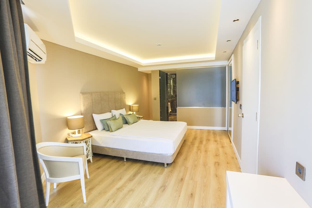 Een moderne hotelkamer met een groot bed, nachtkastjes, een stoel en een televisie.