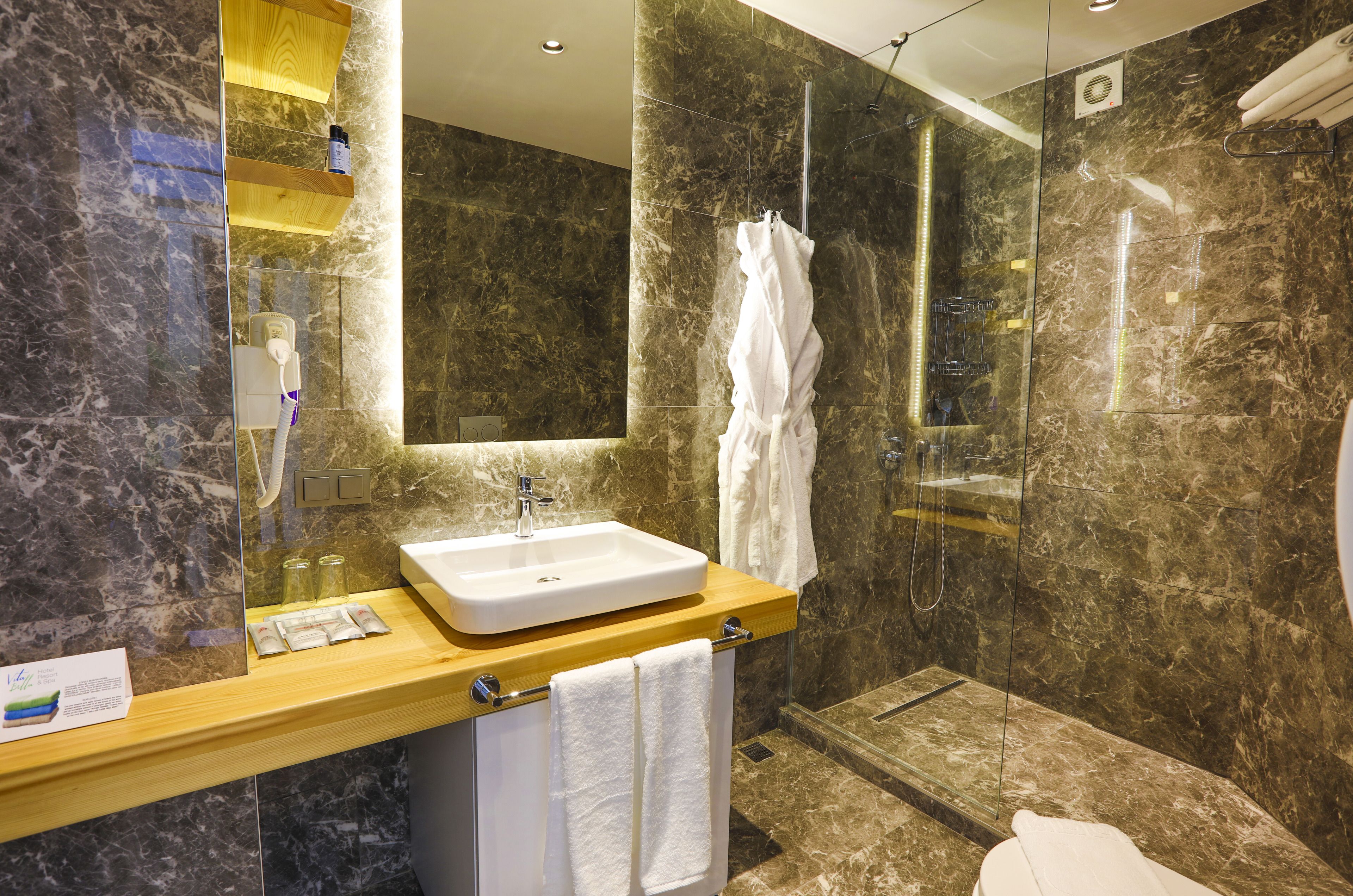 Une salle de bain moderne avec un lavabo en marbre, une douche en verre et un grand miroir.