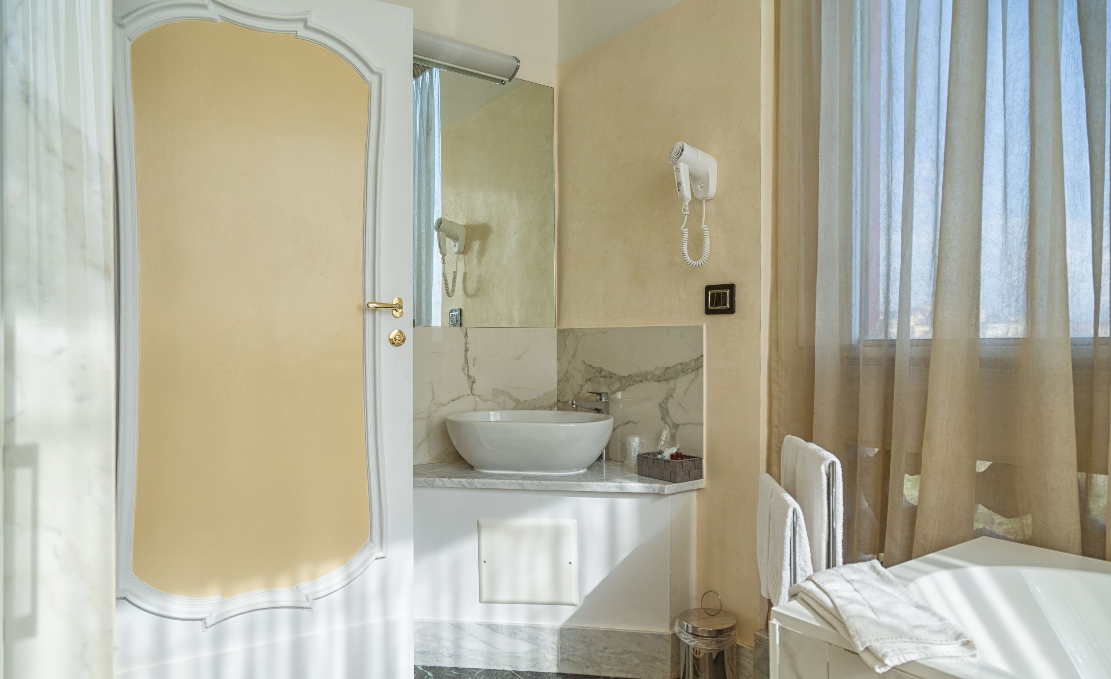 A bathroom with a large sink, a mirror, a hairdryer, and a towel rack.
