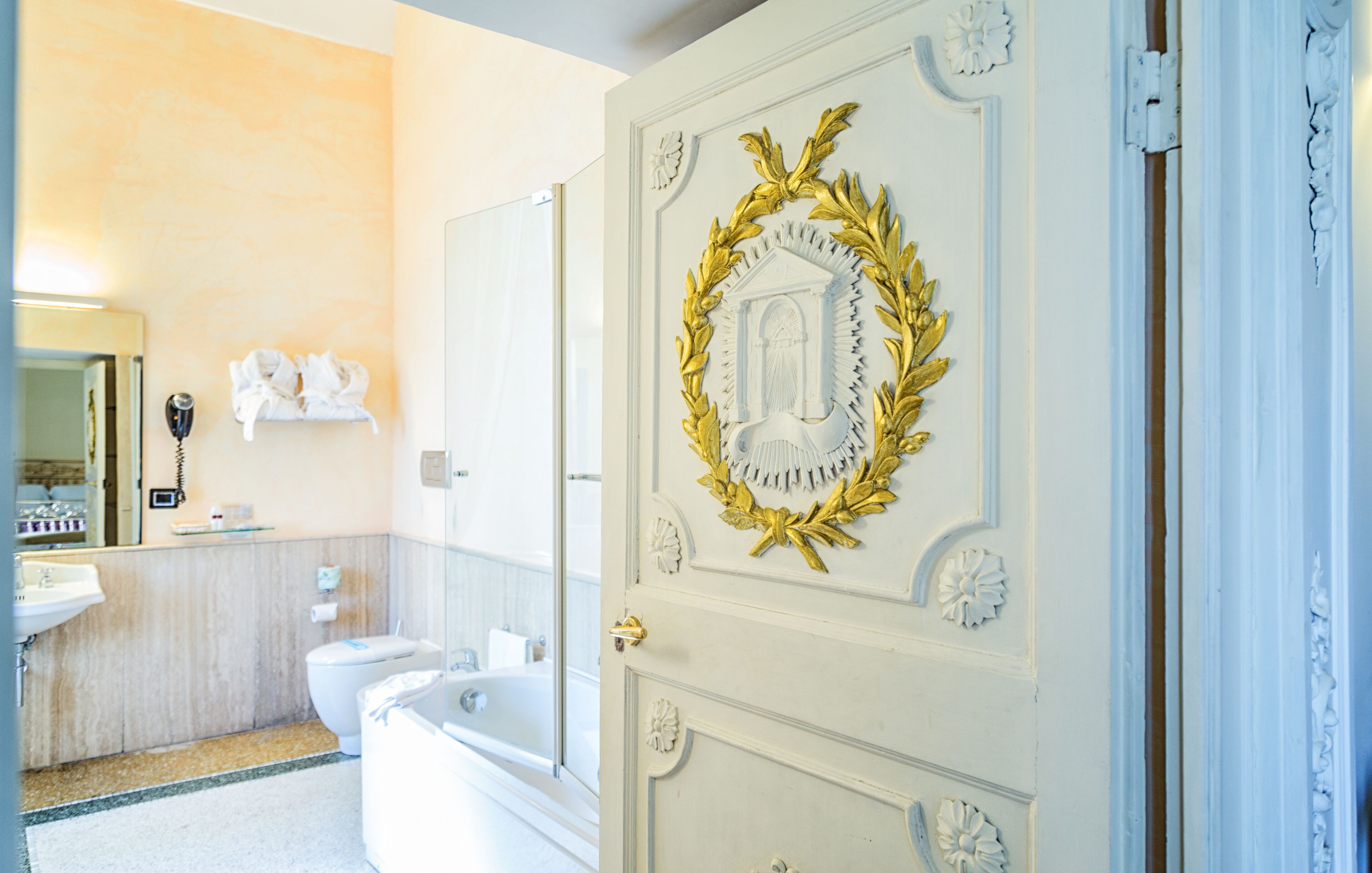 A bathroom with a white sink, toilet, and bathtub. There is a mirror above the sink and a towel rack on the wall.