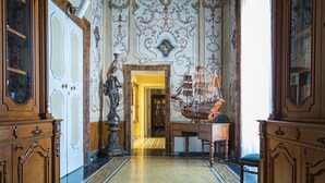 An ornate hallway with a chandelier, wooden furniture, and a decorative ship model. - Villa Signorini Events & Hotel (Ercolano)