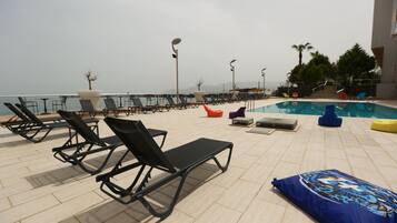 A rooftop pool area with lounge chairs and a swimming pool.