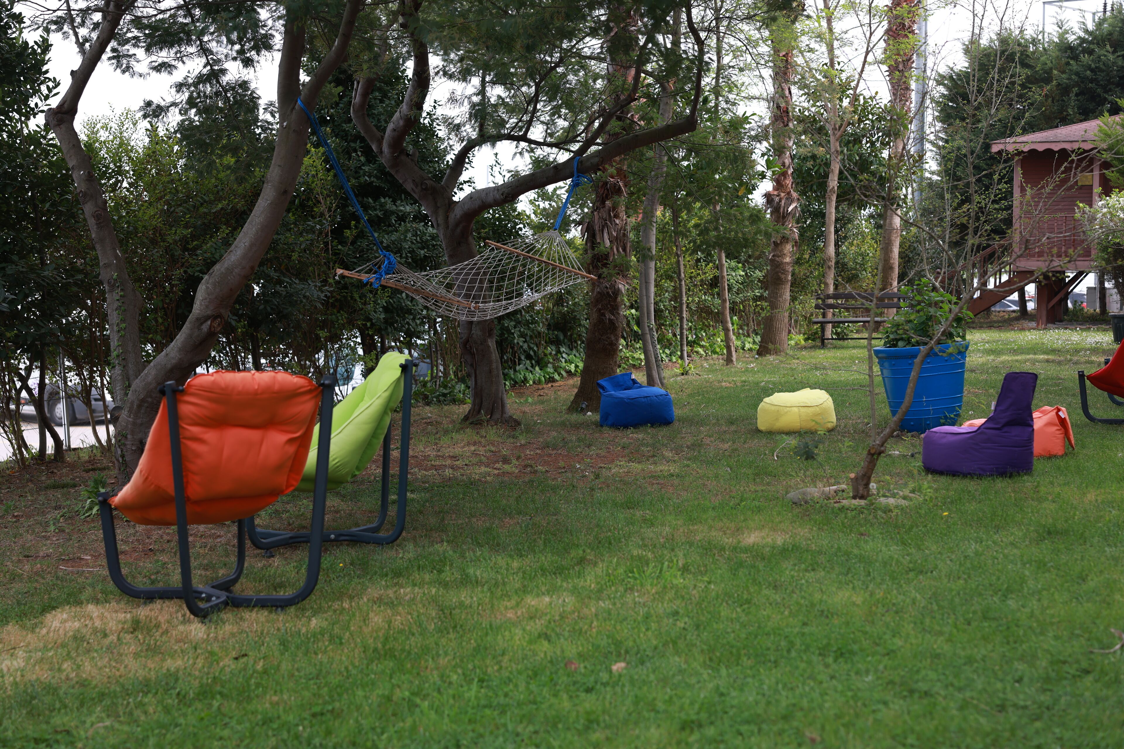 Outdoor seating with chairs and bean bags, a hammock, and a small tree.