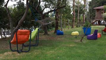 Outdoor seating with chairs and bean bags, a hammock, and a small tree.