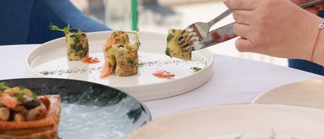 A dining table with various dishes, including a plate with rolled appetizers and a plate with salmon and vegetables.