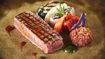 A steak with grill marks, grilled vegetables, and a small round item on a plate.
