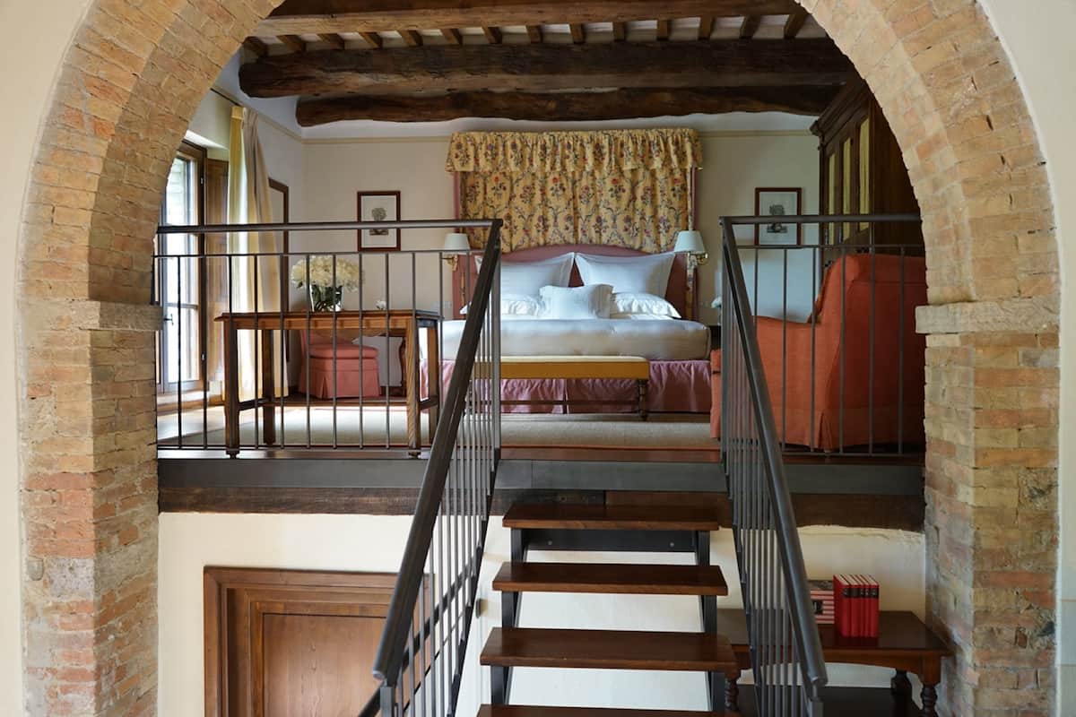 A bedroom with a bed, a staircase, and a view of the outside.