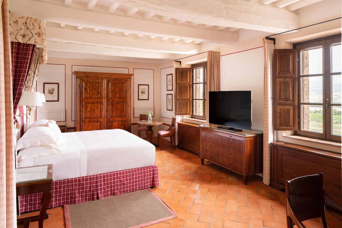 A hotel room with a bed, a desk, a television, and a window with a view.