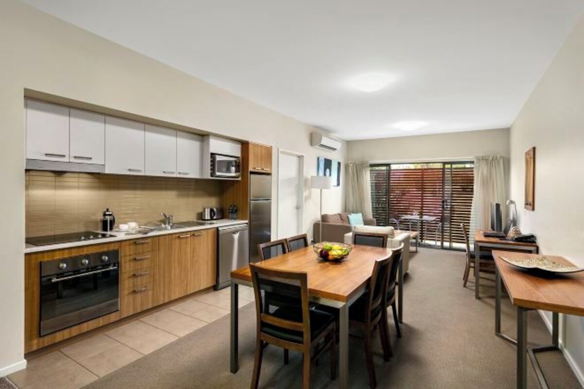 Una cocina moderna con armarios de madera, una mesa de comedor con sillas y vistas al área de estar.