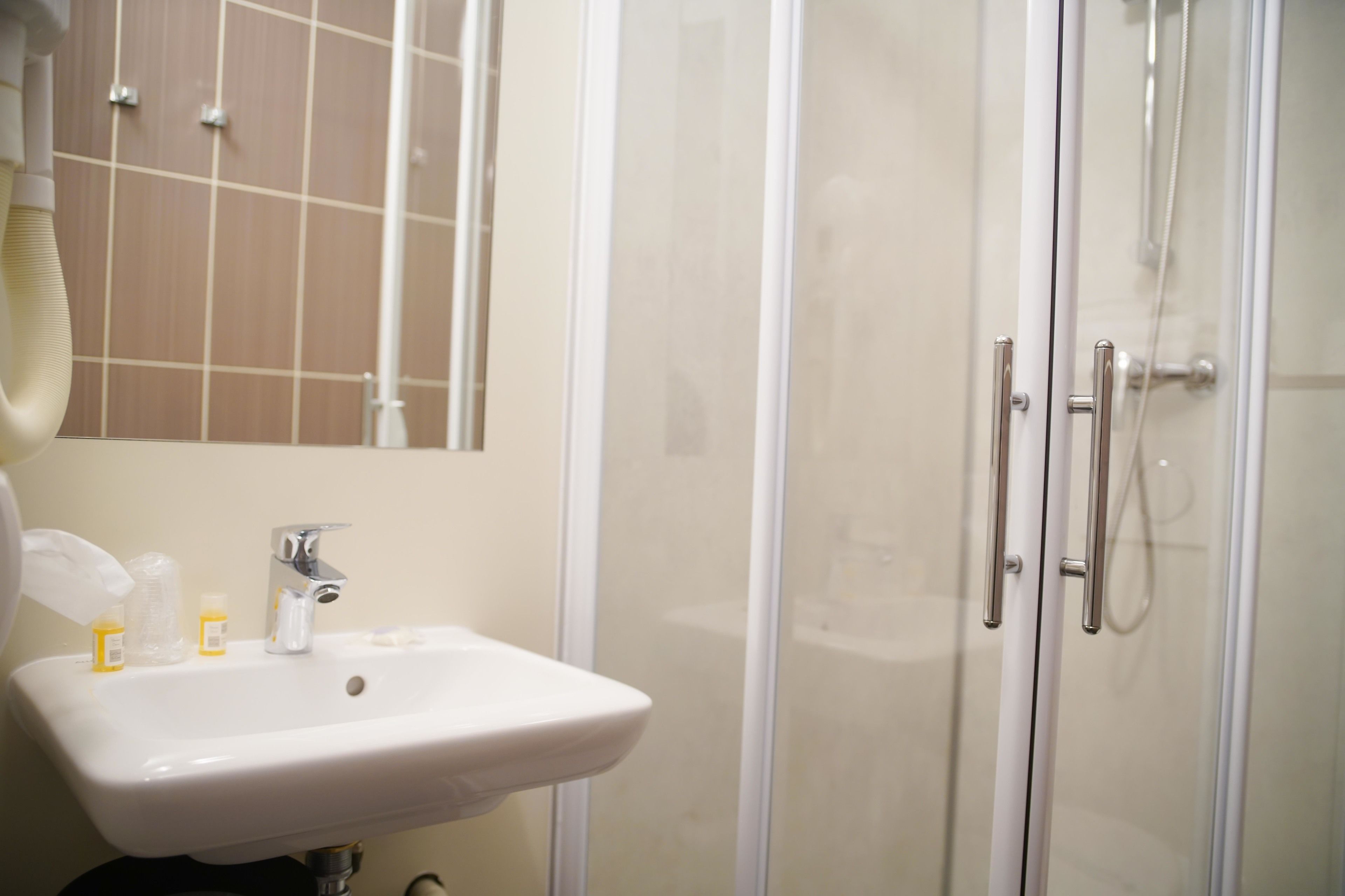 Un baño con lavamanos blanco, espejo y cabina de ducha.