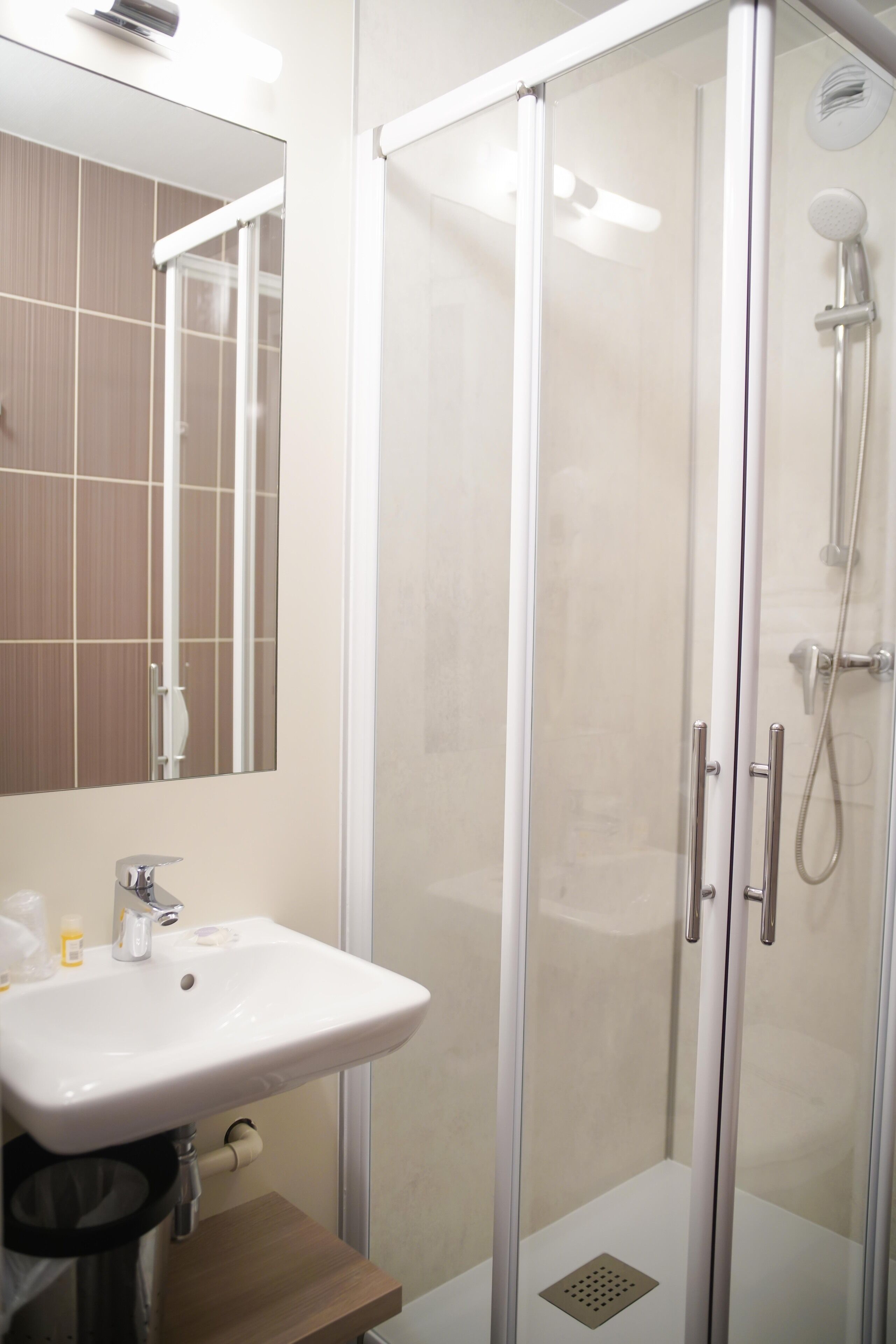 A modern bathroom with a glass-enclosed shower, a white sink, and a mirror.