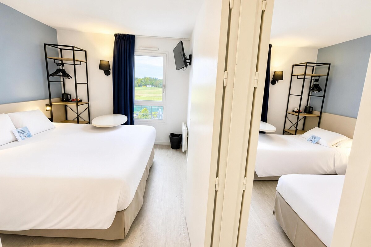 Habitación de hotel con dos camas, una ventana con vistas, televisor y escritorio con silla.