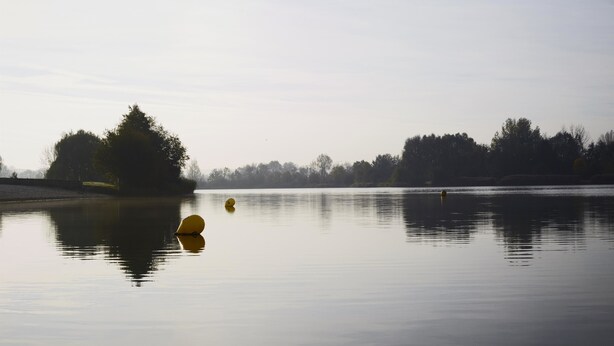 A calm lake with a buoy and a boat.